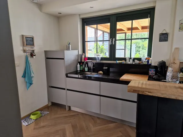 Keuken met grijze en zwarte fronten en een houten bar